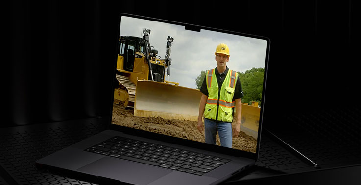 Computer in a dark room with equipment and worker on screen